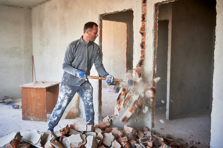 dismantler breaking septum between rooms with hand's sledgehammer