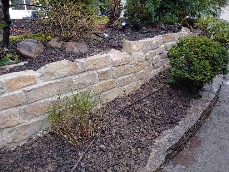 Muret en pierre bordant un massif de jardin